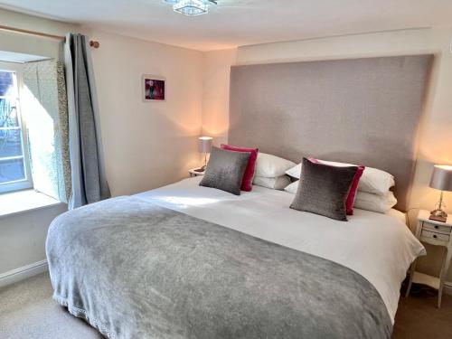 a bedroom with a large white bed with red pillows at Gate Cottage in Matlock