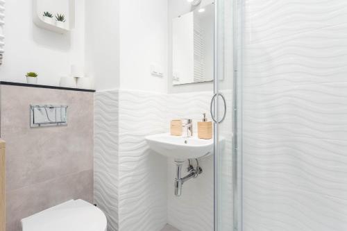 a white bathroom with a sink and a shower at Chill Apartments Airport Ursynów in Warsaw