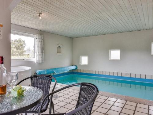 - une piscine avec une table et des chaises dans la chambre dans l'établissement Holiday Home Gunny - 500m to the inlet in Western Jutland by Interhome, à Blåvand