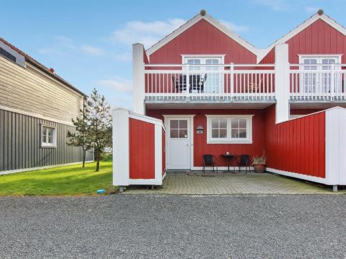 a red house with a white balcony and a red door at Apartment Guthir - 1-2km from the sea in Western Jutland by Interhome in Blåvand