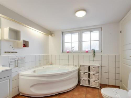 a white bathroom with a tub and a toilet at Apartment Guthir - 1-2km from the sea in Western Jutland by Interhome in Blåvand