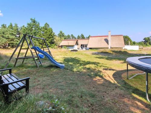 a playground with a slide and a bench in a field at Holiday Home Gerdis - 1-6km from the sea in Western Jutland by Interhome in Blåvand