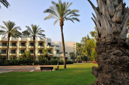 a building with palm trees in front of a park at Kinar Galilee in Kinar