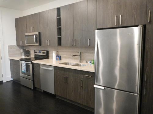 a kitchen with wooden cabinets and a stainless steel refrigerator at Modern Urban Oasis with Private Parking in Downtown Houston in Houston