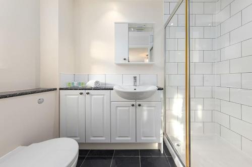 Baño blanco con lavabo y aseo en Flourish Apartments - Footbury House - Orpington, en Orpington