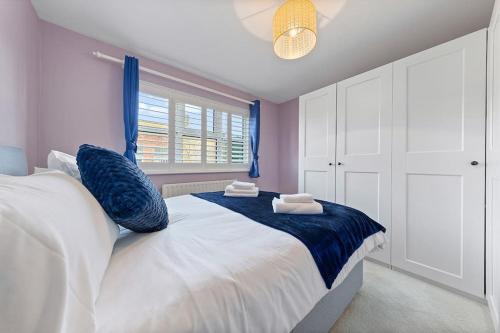 a bedroom with a large white bed with blue pillows at Flourish Apartments - Footbury House - Orpington in Orpington