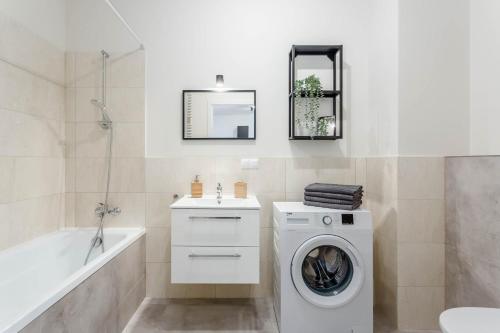 a white bathroom with a washing machine and a bath tub at Chill Apartments Airport Ursynów in Warsaw