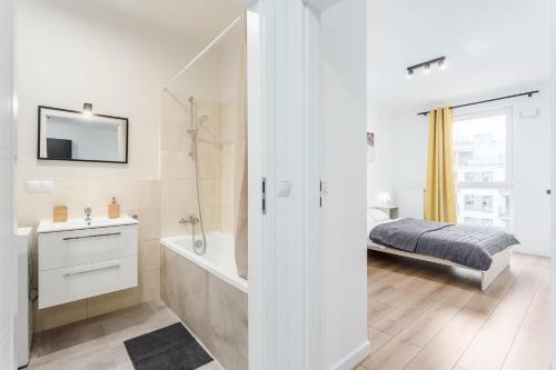 a white bathroom with a bed and a bath tub at Chill Apartments Airport Ursynów in Warsaw