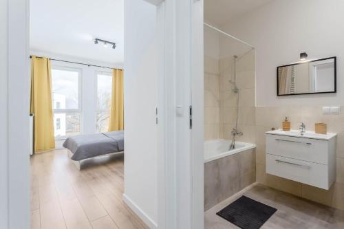 a bathroom with a tub and a sink and a mirror at Chill Apartments Airport Ursynów in Warsaw