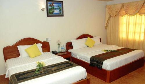 ein Hotelzimmer mit 2 Betten und gelben Kissen in der Unterkunft Lux Guesthouse in Battambang