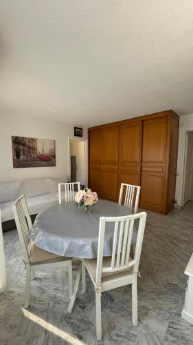 a dining room table with three chairs and flowers on it at JUAN LES PINS, T2 Cosy et confortable, avec PARKING en sous-sol, proche plages et commerces in Antibes