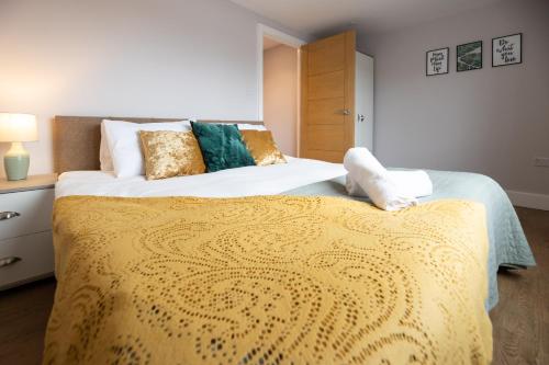 a bedroom with a large bed with a yellow blanket at James Charles Apartments in Milton Keynes