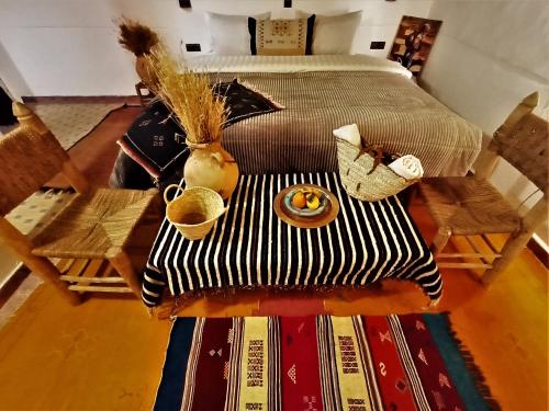 a bedroom with a bed and a table with a vase on it at Riad Bleu Afriqua in Boumalne