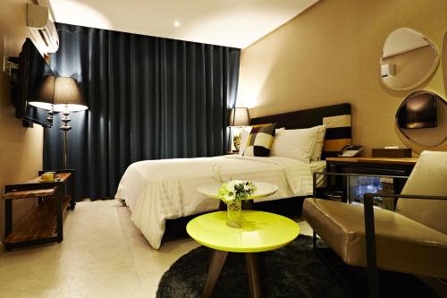 a hotel room with a bed and a table with flowers on it at Hotel Namoo Cheong-ju in Cheongju
