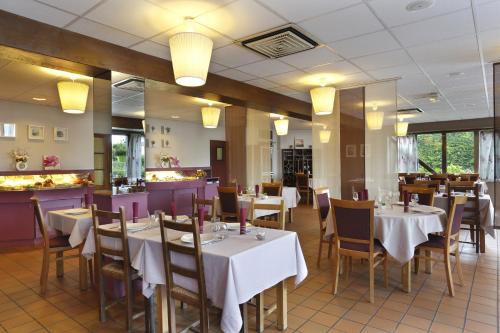 a dining room with tables and chairs and a bar at FastHôtel Blois in Blois