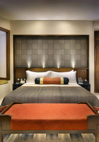 a bedroom with a large bed with a large headboard at The Lalit Great Eastern Kolkata in Kolkata