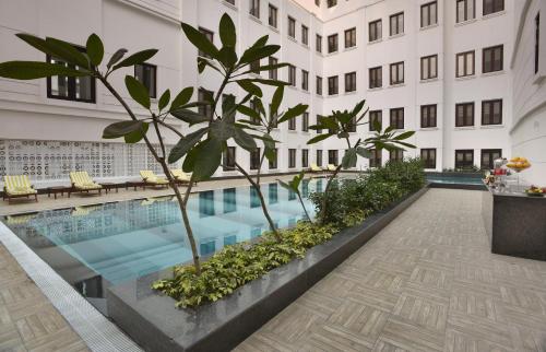 a swimming pool in the middle of a building with trees at The Lalit Great Eastern Kolkata in Kolkata