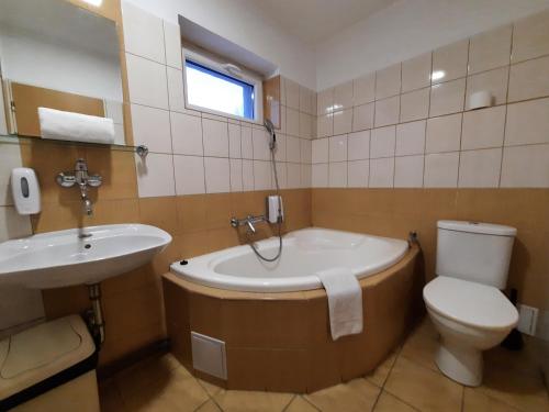 a bathroom with a tub and a toilet and a sink at Hotel Boršičanka in Havířov