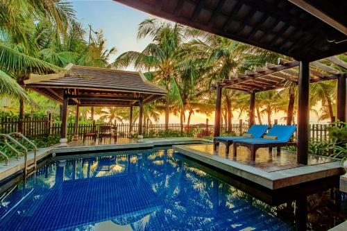 a swimming pool with two blue chairs next to a house at Anja Beach Resort & Spa in Phu Quoc