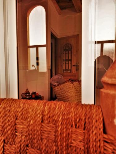 a wicker chair in a room with two windows at Riad Bleu Afriqua in Boumalne