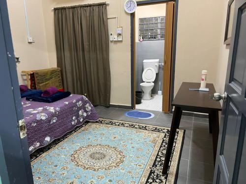 uma casa de banho com uma cama, um WC e um tapete em Homestay riha 2 em Kota Bharu