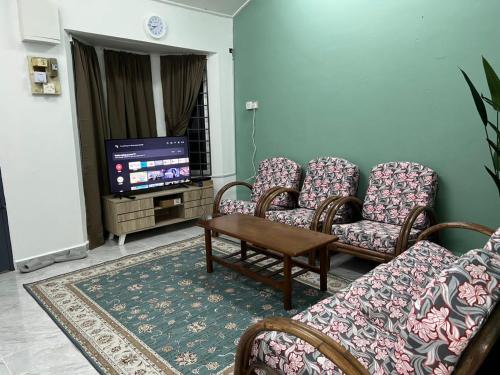 uma sala de estar com cadeiras, uma mesa e uma televisão em Homestay riha 2 em Kota Bharu