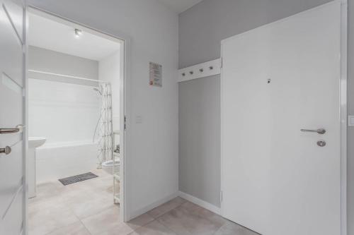 a white bathroom with a shower and a glass door at Chill Apartments Airport Ursynów in Warsaw