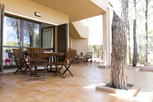 eine Terrasse mit einem Tisch, Stühlen und einem Baum in der Unterkunft Casa Sara&Chiara in Santa Margherita di Pula