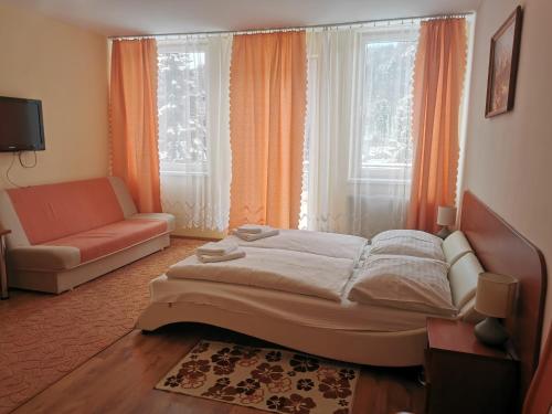 a bedroom with a bed and a couch and a window at Penzion Zornicka in Bardejovské Kúpele