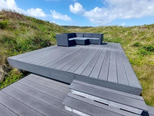 um banco sentado no topo de um deque de madeira em Holiday Home Beneta - 300m from the sea in Western Jutland by Interhome em Hvide Sande