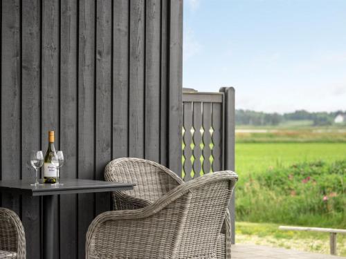 a table with two chairs and a bottle of wine at Holiday Home Mara - from the sea by Interhome in Ringkøbing