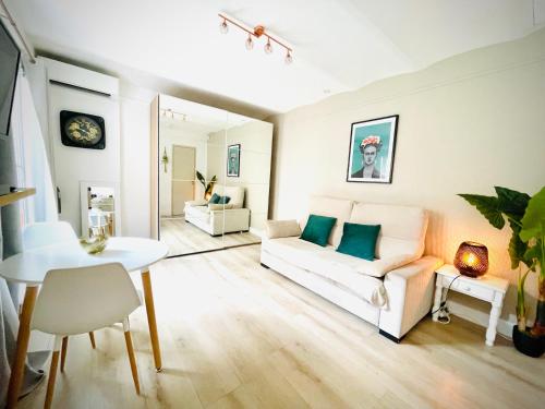 ein Wohnzimmer mit einem weißen Sofa und einem Tisch in der Unterkunft Maisonnette studio bas Suquet, 200m plages, 700m palais, au calme in Cannes