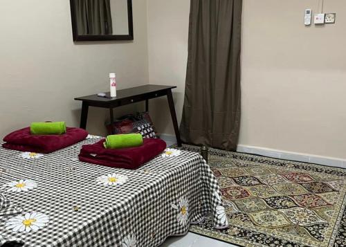 um quarto com duas camas e uma mesa com almofadas verdes em Homestay riha 2 em Kota Bharu