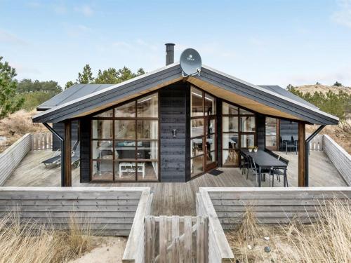 uma casa num deque de madeira com uma mesa em Holiday Home Sila - 800m from the sea in Western Jutland by Interhome em Hvide Sande