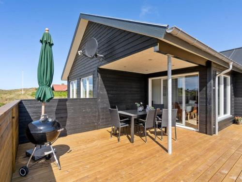 einen Grill und einen Regenschirm auf einer Holzterrasse in der Unterkunft Holiday Home Alvhild - from the sea by Interhome in Ringkøbing