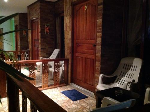 a porch with two white chairs and a wooden door at Ruan Mai Naiyang Beach Resort in Nai Yang Beach