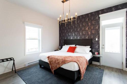 a bedroom with a large bed with a black accent wall at Brand New Light filled Mile End Flat by Denstays in Montreal