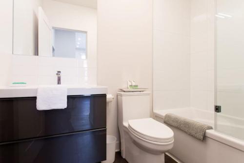 La salle de bains blanche est pourvue de toilettes et d'un lavabo. dans l'établissement Brand New Light filled Mile End Flat by Denstays, à Montréal