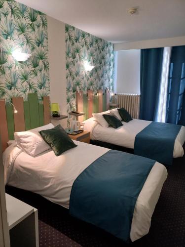 two beds in a hotel room with blue curtains at Hôtel Le Centre in Les Herbiers
