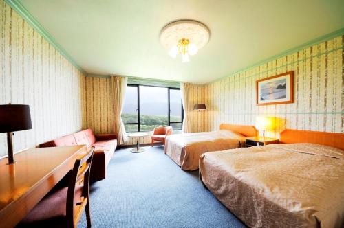ein Hotelzimmer mit 2 Betten und einem Sofa in der Unterkunft Hachijo View Hotel in Hachijō