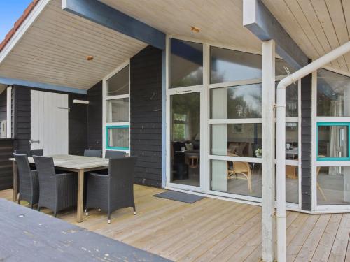 une maison dotée d'une terrasse en bois avec une table et des chaises dans l'établissement Holiday Home Andrie - 800m from the sea in Western Jutland by Interhome, à Hvide Sande