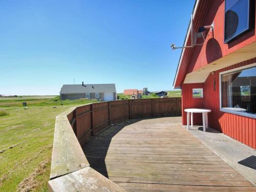 een houten loopbrug naast een rood gebouw bij Holiday Home Beatrice - 150m from the sea in Western Jutland by Interhome in Lemvig