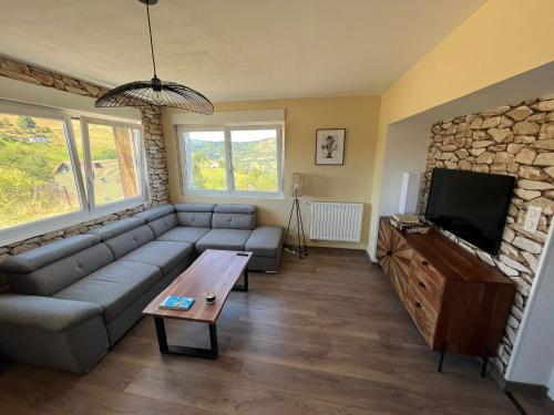 a living room with a couch and a tv at Gîtes BEL'M in La Bresse