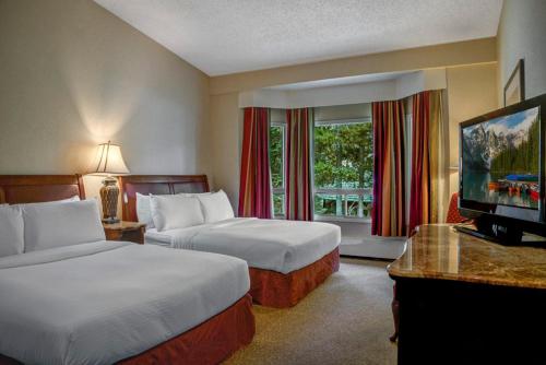 a hotel room with two beds and a flat screen tv at Lake Louise Inn in Lake Louise