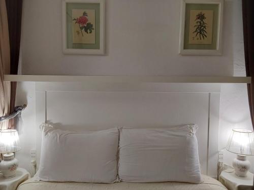 a white bed with a white headboard and two lamps at B&B Ma Maison in Govone
