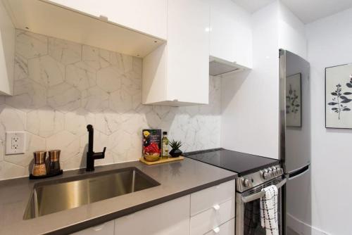 a kitchen with a stainless steel sink and white cabinets at Palms Little Italy Studio with full bathroom by Denstays in Montréal