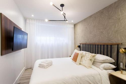 a bedroom with a white bed with a flat screen tv at Palms Little Italy Studio with full bathroom by Denstays in Montréal