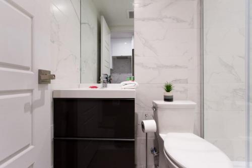 a white bathroom with a toilet and a sink at Palms Little Italy Studio with full bathroom by Denstays in Montréal