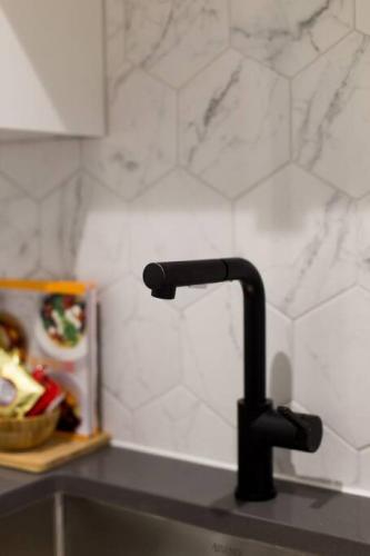 a kitchen sink with a black faucet on a counter at Palms Little Italy Studio with full bathroom by Denstays in Montréal