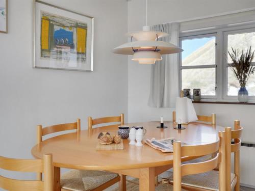 ein Esszimmer mit einem Holztisch und Stühlen in der Unterkunft Holiday Home Tabea - 150m from the sea in NW Jutland by Interhome in Løkken